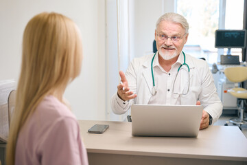 Female patient consulting with male doctor in clinic office