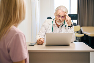 Woman patient consulting with male doctor in clinic office
