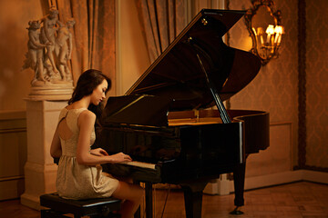 Mansion, woman and piano with musician playing, lounge and pianist in ballroom with luxury instrument. Entertainment, palace and vintage fashion of sound artist with song and dark glamour with style
