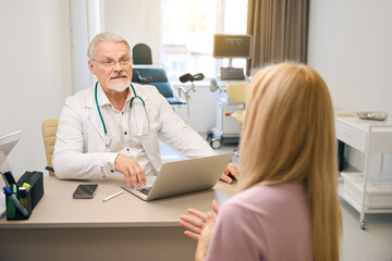 Female patient consulting with medical specialist in clinic office - 797060124