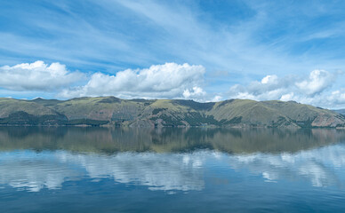 lagoon in the foreground with mountains with forests in the background and cloudy sky in Acomayo,...