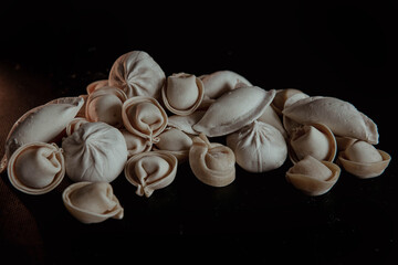 Semi-finished dumplings on a black background