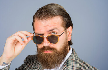 Closeup portrait of serious attractive man takes off sunglasses. Handsome bearded man in suit...