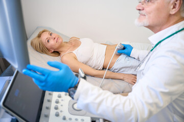 Clinical specialist using ultrasound scan examining pretty lady