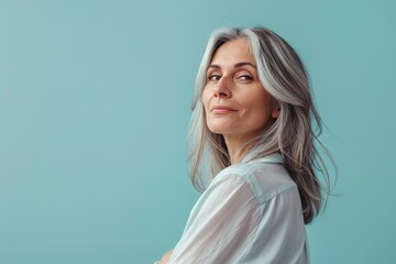 Fototapeta premium A woman with gray hair is standing in front of a blue wall
