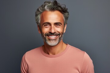 A man with a mustache and gray hair is smiling and wearing a pink shirt