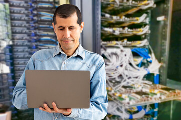 Waist up portrait of man as network engineer in server room using laptop