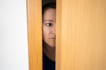 Cropped shot of woman spying and entering through the door as concept of nosy woman
