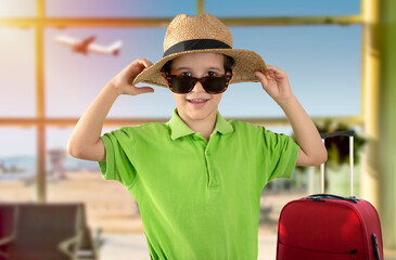 Boy on vacation wearing green t-shirt hat sunglasses at airport happy portrait smiling and looking at the camera. Positive person
