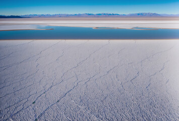 Early morning drone view of salt flats, with shadows stretching long across the textures. AI generated.