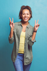 Happy woman, portrait and peace sign with fashion for style, love or care on a blue studio...
