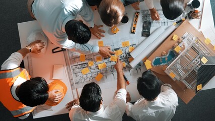 Top down view of skilled engineer team talking while looking at project plan. Aerial view of group...