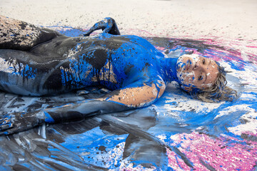 portrait and upper body of expressive sexy woman elegant on the floor in blue, black and white color abstract painted bodypainting woman on the splashed ground