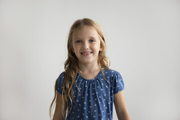 Beautiful little girl in casual blouse posing on gray wall studio background. Portrait of generation Alpha kid, happy childhood, services and commercial offers for children advertisement, copy-space