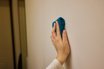 Using a blue towel, the person cleans the wall with a swift wrist gesture