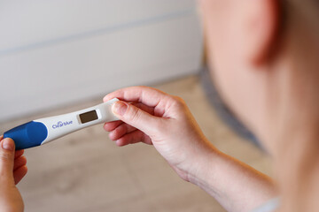 Close up top view of a woman holding a digital pregnancy test with empty display
