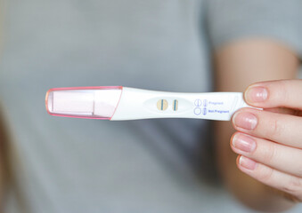 Close up of a woman holding a positive pregnancy test