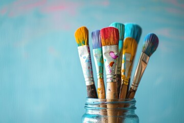 Colorful paintbrushes in a glass jar against a vibrant background