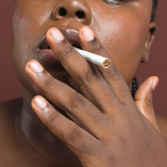 Brown skinned woman smoking a cigarette, dark skin woman with a cigarette between her lips