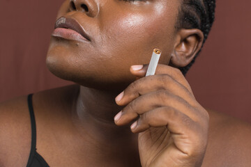 Brown skinned woman with a cigarette, dark skin woman with a cigarette between her fingers