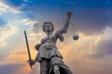 statue of lady justice under dramatic sunset sky