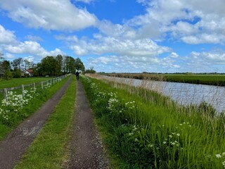Fototapeta na wymiar Cycling on a sunny spring day beside a Dutch waterway near Reeuwijk, The Netherlands