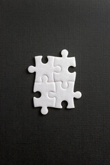 Four white elements from a jigsaw puzzle on black background. Concept of team work, business,...