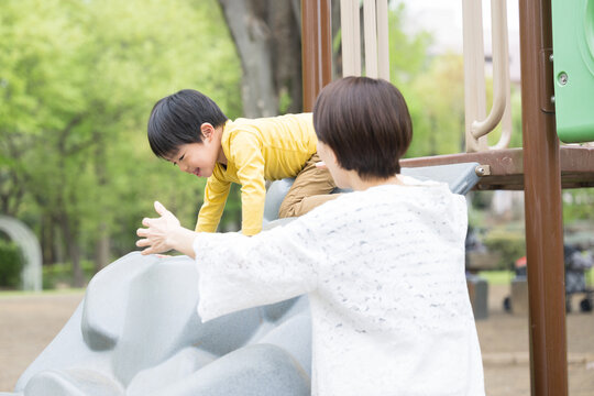 A child playing in the park with his mother Image of childcare and child rearing