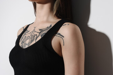 Woman with cool tattoos on light background, closeup