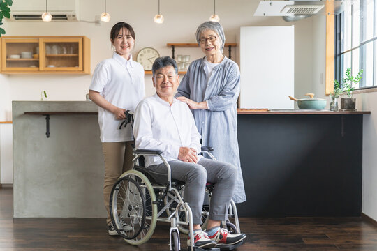車椅子に座る高齢者男性と高齢者女性と介護士・理学療法士・介護スタッフの女性
