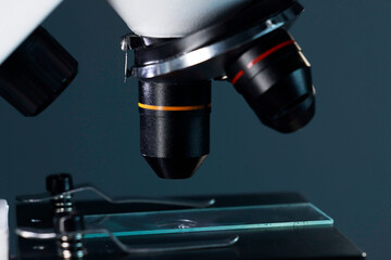 Microscope with glass slide on dark background, closeup