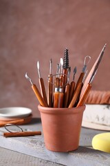 Clay and set of crafting tools on grey wooden table in workshop, closeup