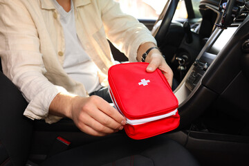 Man with first aid kit inside car, closeup