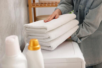 Woman with stack of clean towels indoors, closeup