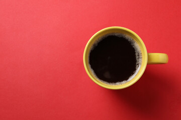Cup of aromatic coffee on red background, top view. Space for text