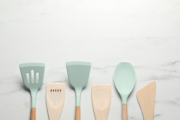 Different spatulas on white marble table, flat lay. Space for text