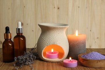 Obraz na płótnie Canvas Aromatherapy. Scented candles, bottles, lavender and sea salt on bamboo mat