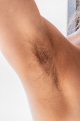 Closeup of long dark hair growing under arm of young female. Concept of hygiene, natural beauty,...