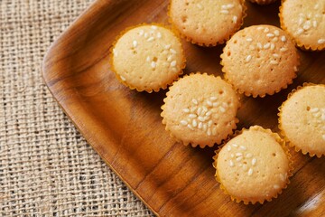 Sesame cake on a wooden plate on a brown cloth background, photographed with studio lights