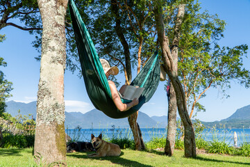 Woman reading a book in a comfortable hammock in her garden