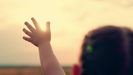 Hand happy baby at sunset. Silhouette hand of kid close-up in sun. Child stretches hand to sun. Silhouette palm pull to sun. Religion lends help hand. Prayer in religion. Concept faith religion prayer