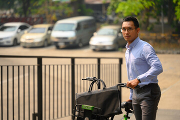 Businessman pushing bicycle while going to work on a sunny morning. Eco transportation