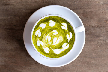 Top view of a cup of matcha green tea with milk cream On the wooden table in the living room in the...