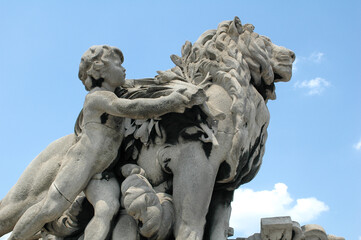 A cherub interacts with a lion in a stone sculpture