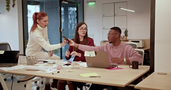 Colleagues in casual attire are actively engaged in discussion and work in a well-lit, contemporary workspace, their comfortable clothing reflecting the modern, collaborative culture of the office.