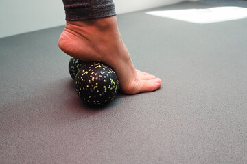Massaging foot with a relaxing roll. Woman massaging foot with massage ball. Myofascial relaxation of foot muscles. Preventing foot fatigue