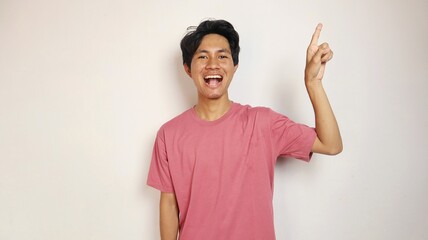 excited young handsome asian man happy, cheerful and excited posing pointing to the top side with isolated white background