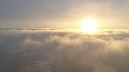 Sunset in fog white clouds sky. Aerial drone flight view. Epic panoramic overview the bright yellow orange sun above the fast moving surface fog covering Antarctic. Overwhelmed scape. Amazing .