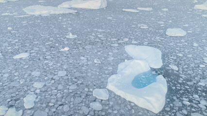 Melting Iceberg Pool Brash Ice Aerial Zooming Out. Massive Snow Ice with Hole Float in Antarctica...