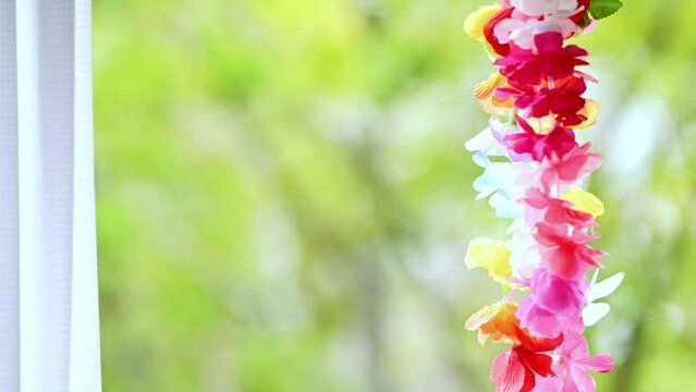 新緑の緑の見える窓際に吊るされたフラワーレイ